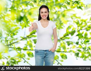 advertisement, gesture, clothing and people concept - happy smiling young woman or teenage girl in white t-shirt showing thumbs up over green natural background