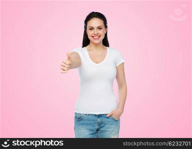 advertisement, gesture, clothing and people concept - happy smiling young woman or teenage girl in white t-shirt showing thumbs up over pink background