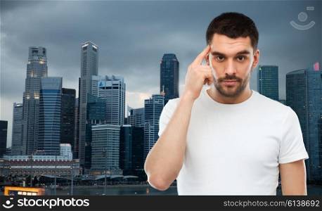 advertisement, idea, business, mind and people concept - man pointing finger to his temple over evening singapore city background