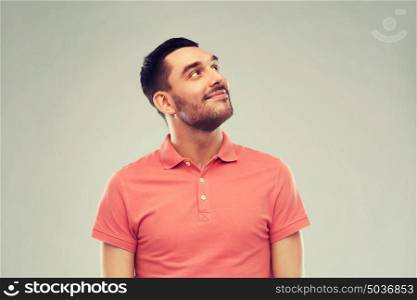 advertisement, idea, inspiration and people concept - happy smiling young man in polo t-shirt looking up over gray. smiling man looking up over gray background