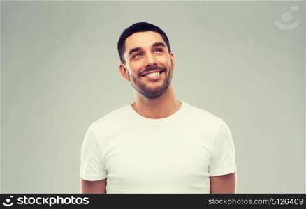 advertisement, idea, inspiration and people concept - happy smiling young man looking up over gray. smiling man looking up over gray background