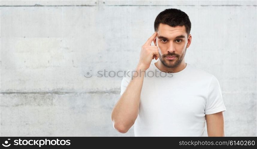 advertisement, idea, inspiration and people concept - man pointing finger to his temple over gray wall background