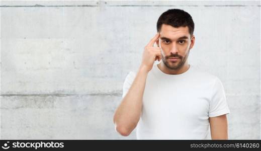advertisement, idea, inspiration and people concept - man pointing finger to his temple over gray wall background