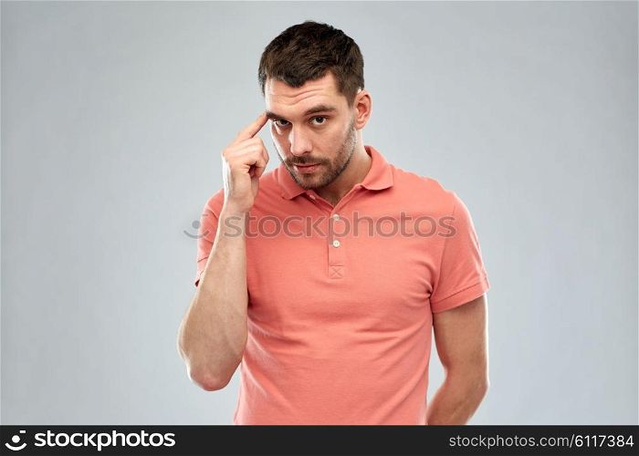 advertisement, idea, inspiration and people concept - man pointing finger to his temple over gray background