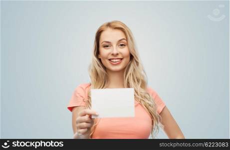 advertisement, invitation, message and people concept - smiling young woman or teenage girl with blank white paper card over gray background