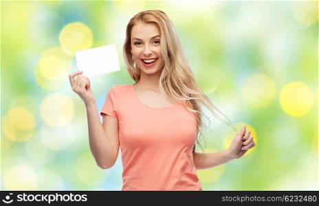 advertisement, invitation, message and people concept - smiling young woman or teenage girl with blank white paper card over summer green lights background