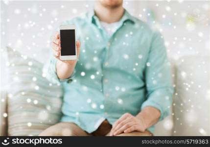 advertisement, people, home and technology concept - close up of man showing smartphone blank screen sitting on couch at home
