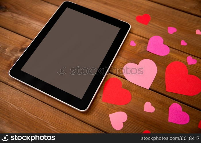 advertisement, romance, valentines day and holidays concept - close up of tablet pc computer and hearts on wood