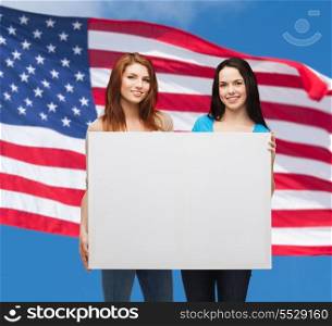 advertisement, sale and people concept - smiling young girls with blank white board over american flag background