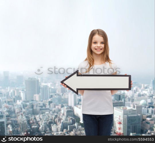 advertising and child concept - smiling little girl with blank arrow pointing left