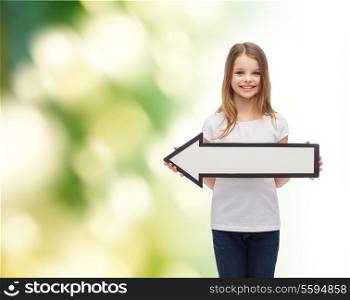 advertising and child concept - smiling little girl with blank arrow pointing left