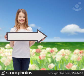 advertising and child concept - smiling little girl with blank arrow pointing right