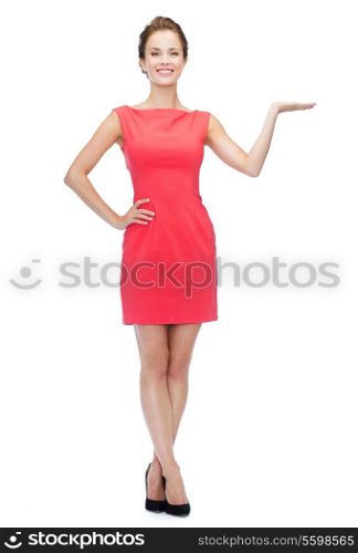 advertising and happy people concept - smiling woman in red dress holding something imaginary on palm of her hand