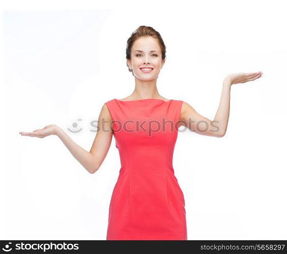 advertising and happy people concept - smiling woman in red dress holding something imaginary on palms of her hands