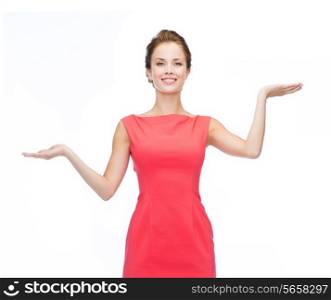 advertising and happy people concept - smiling woman in red dress holding something imaginary on palms of her hands