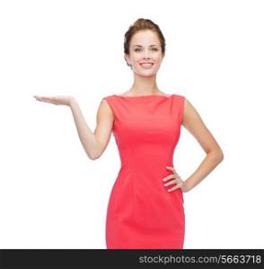 advertising and happy people concept - smiling woman in red dress holding something imaginary on palm of her hand