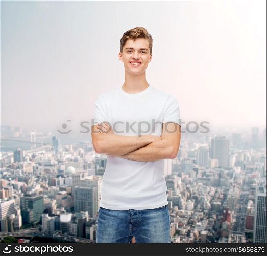 advertising and people concept - smiling young man in blank white t-shirt over city background