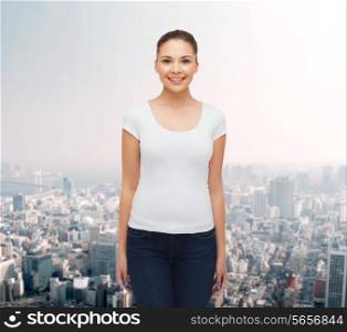 advertising and people concept - smiling young woman in blank white t-shirt over city background