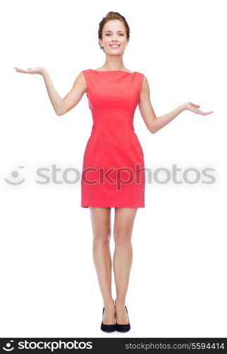 advertising and people concept - smiling young woman in red dress holding something on palm of her hands