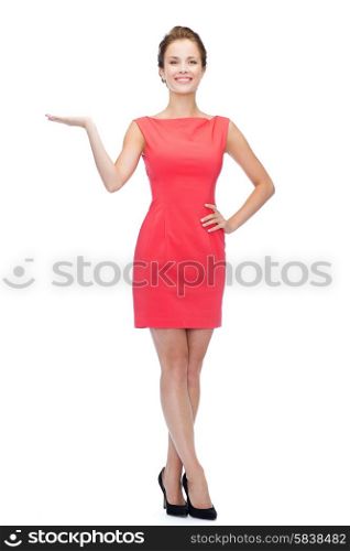 advertising and people concept - smiling young woman in red dress holding something on palm of her hand