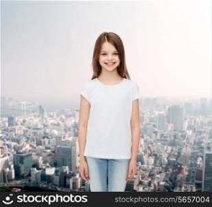 advertising, childhood and people concept - smiling little girl in white blank t-shirt over city background