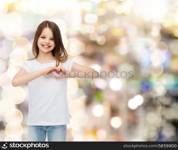 advertising, childhood, charity, holidays and people - smiling girl in white t-shirt making heart-shape gesture over sparkling background