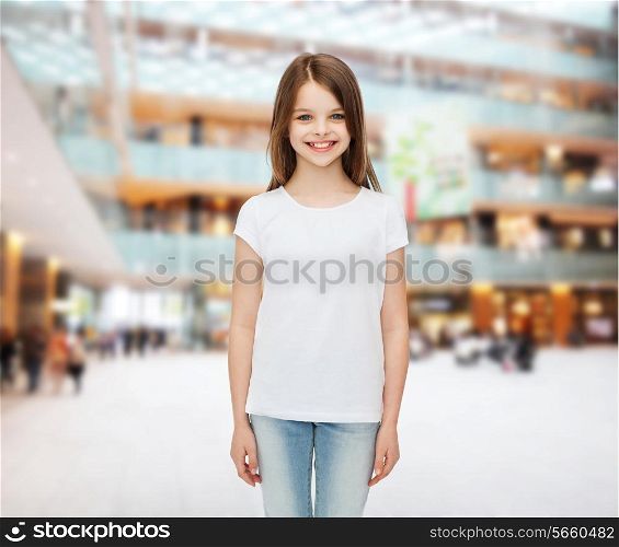 advertising, childhood, consumerism and people - smiling little girl in white blank t-shirt over shopping center background