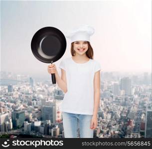 advertising, childhood, cooking and people - smiling girl in white t-shirt and cooking hat holding pan over blue background