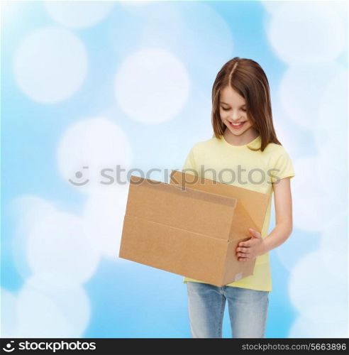 advertising, childhood, delivery, mail and people - smiling little girl holding open cardboard box and looking into it over blue background