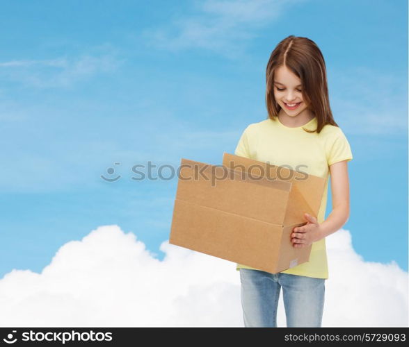 advertising, childhood, delivery, mail and people - smiling little girl holding open cardboard box and looking into it over blue background
