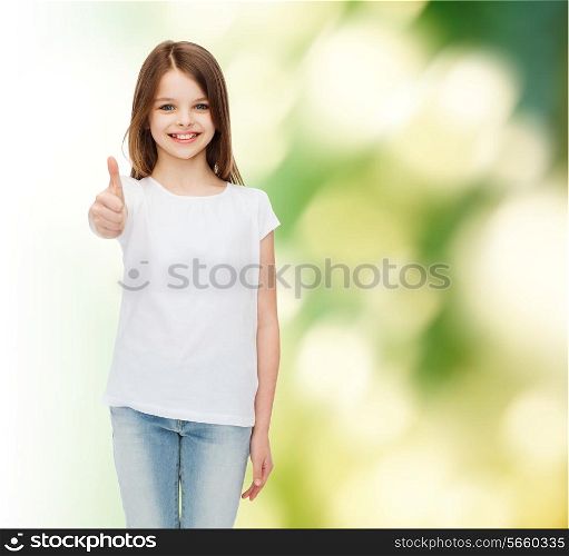 advertising, childhood, ecology and people - smiling little girl in white blank t-shirt showing thumbs up gesture over green background