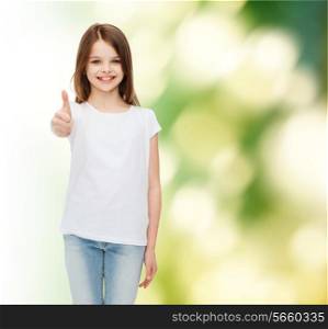 advertising, childhood, ecology and people - smiling little girl in white blank t-shirt showing thumbs up gesture over green background
