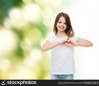 advertising, childhood, ecology, charity and people - smiling little girl in white t-shirt making heart-shape gesture over green background