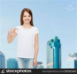 advertising, childhood, gesture and people concept - smiling girl in white shirt pointing finger on herself over business center background