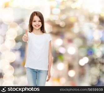 advertising, childhood, gesture, holidays and people - smiling girl in white t-shirt showing thumbs up gesture over sparkling background