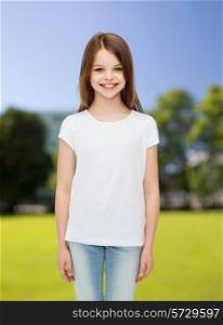 advertising, childhood, nature and people - smiling little girl in white blank t-shirt over green park background