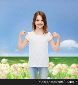 advertising, childhood, nature, gesture and people concept - smiling girl in white t-shirt pointing fingers on herself over field background