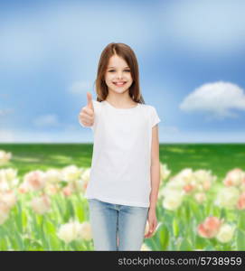 advertising, childhood, nature, gesture and people concept - smiling girl in white t-shirt showing thumbs up over flower field background