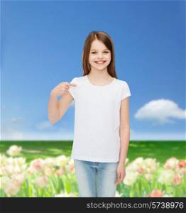 advertising, childhood, nature, gesture and people concept - smiling girl in white t-shirt pointing finger on herself over field background