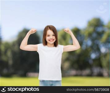 advertising, childhood, nature, gesture and people - smiling little girl in white blank t-shirt with raised arms over green park background