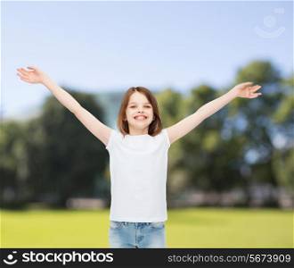 advertising, childhood, nature, gesture and people - smiling little girl in white t-shirt with stretched out arms over green park background