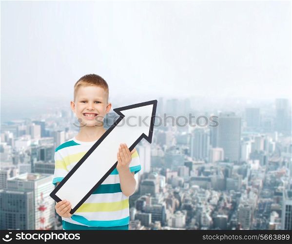 advertising, direction and childhood concept - smiling little boy with white blank arrow pointing right over city background