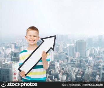 advertising, direction and childhood concept - smiling little boy with white blank arrow pointing right over city background