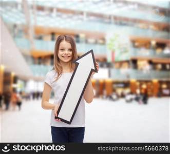 advertising, direction, consumerism and childhood concept - smiling little girl with white blank arrow pointing up over shopping center background