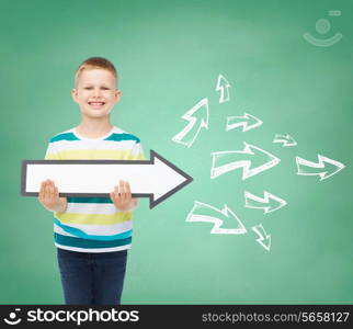 advertising, direction, education and childhood concept - smiling little boy with white blank arrow pointing right over green board with doodles background