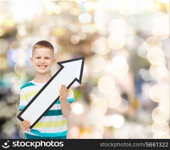 advertising, direction, holidays and childhood concept - smiling little boy with white blank arrow pointing up over sparkling background