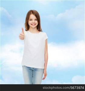 advertising, dream, childhood, gesture and people - smiling little girl in white blank t-shirt showing thumbs up over cloudy sky background