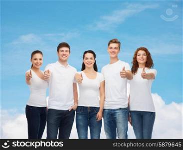 advertising, dream, future and people concept - group of smiling teenagers in white blank t-shirts showing thumbs up over blue sky with white cloud background