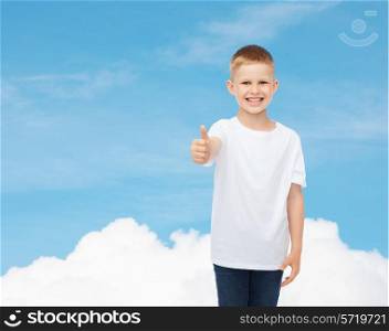 advertising, dream, gesture, people and childhood concept - smiling little boy in white blank t-shirt showing thumbs up over sky background