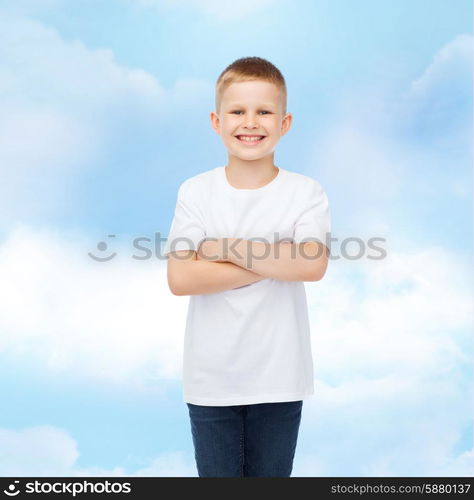 advertising, dream, people and childhood concept - smiling little boy in white blank t-shirt over cloudy sky background